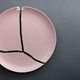A broken pink ceramic plate on a gray background. view from above. The concept of diet, old things - PhotoDune Item for Sale