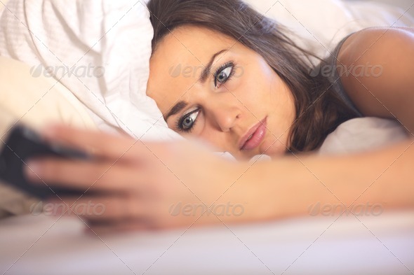Woman on Bed Reading a Text Message - Stock Photo - Images