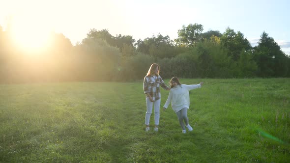 Happy young mum and daughter play together outdoor enjoy beautiful field