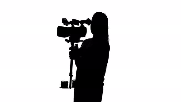 Videographer Shoots Video in the Studio. White. Silhouette alt