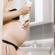 Beautiful pregnant woman in bathroom applying cream on her belly skin.  - PhotoDune Item for Sale