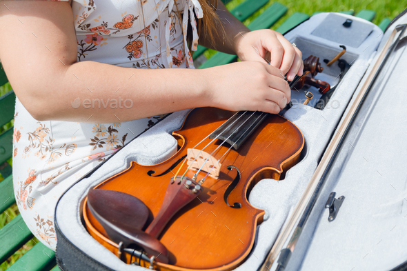 top view unrecognizable female artist on street unzipping violin from case to take it out