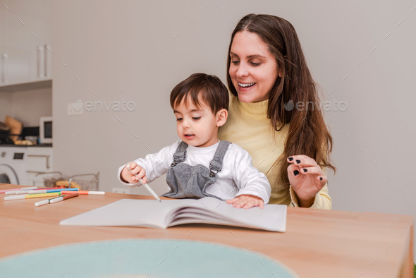 Mother Encouraging Her Little Son as He Learns to Draw with Markers at Home