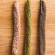 Three different smoked dried sausages hanging on wooden wall. - PhotoDune Item for Sale