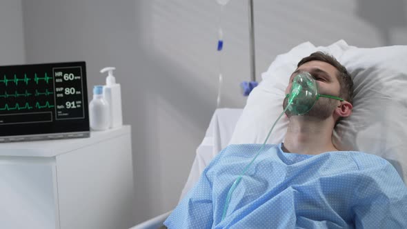 The Man Lies on the Bed in the Hospital in Oxygen Masks and Regains Consciousness alt