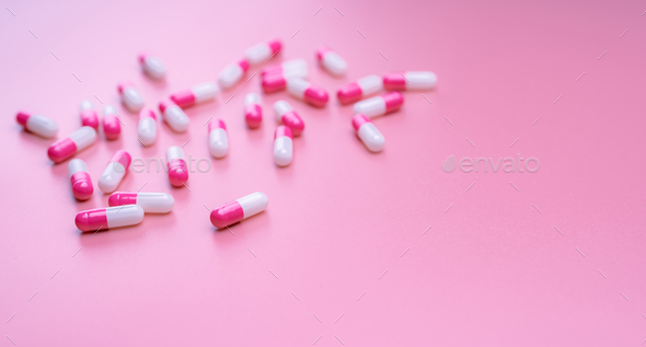 Pink-white antibiotic capsules pill spread on pink background. Pharmacy banner. Antibiotic