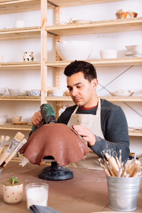 Concentrated male artisan drying clay with heat gun in pottery