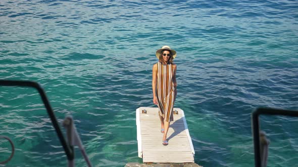 A woman traveling alone on a dock over the Mediterranean Sea in Italy, Europe alt