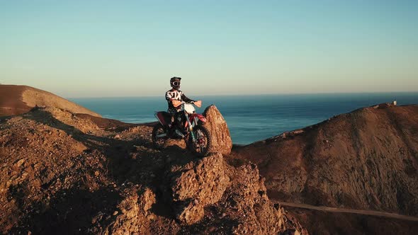 Drone View of Man on Motorbike Extremely Rides Across the Hills with Black Sea on Background in