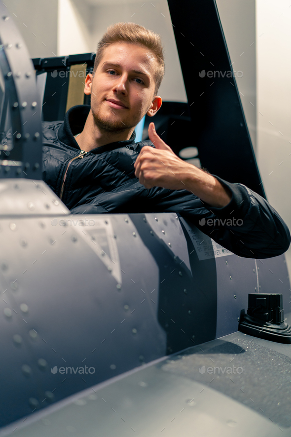 guy sitting in flight simulator of military plane after virtual flight shows hand sign super fun