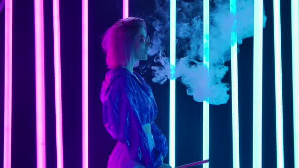 Portrait of a Young Stylish Woman in Sunglasses Smoking a Hookah and Blowing Out Puffs of Smoke alt