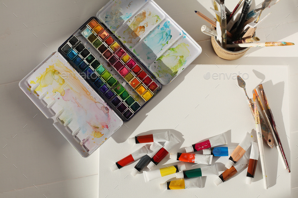 Empty canvas, watercolor and acrylic paints in tubes. Creative mess in artistic workshop.