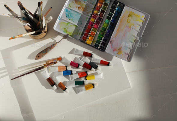 Emptycanvas, watercolor and acrylic paints in tubes. Creative mess in the artistic workshop.