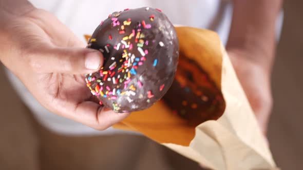 Man Hand Holding a Chocolate Donuts alt
