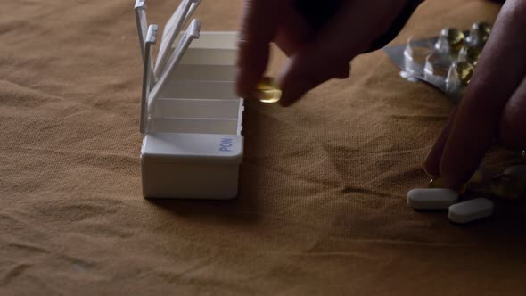 man sorts pills by day of the week in a sorter alt