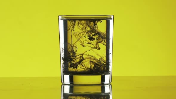 Drop of Black Ink Dripping Into Glass with Water with Swirls alt