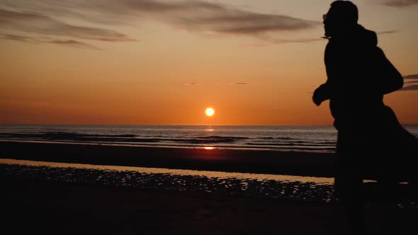 Man running with guitar in back sand beach at sunset. Beautiful, moody shots from the Sony a7iii. alt