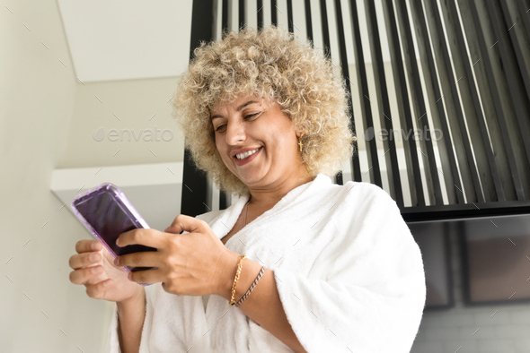 Woman Using Phone in White Robe Enjoying Content