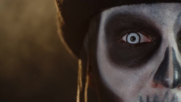 Close-up Shot of Face in Skeleton Halloween Makeup Opening Eyes with White Pupil, Trying To Scare alt