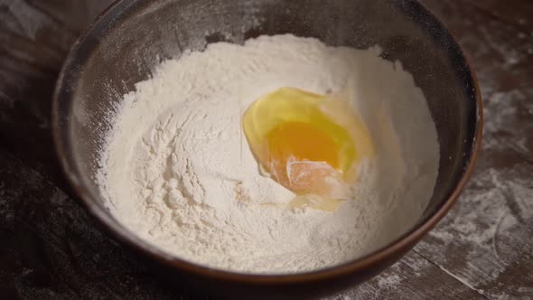 Slow Motion Shot of Egg Falls on Bowl with Flour.