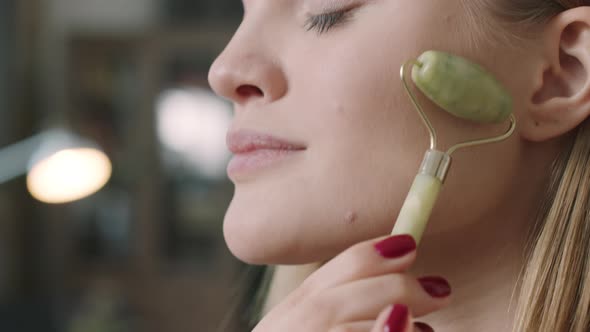 Close Up Of Woman Doing Facial Massage With Roller alt