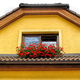 Attic window of yellow stone house decorated with red geranium - PhotoDune Item for Sale