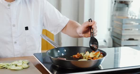 Young Chef Cooking Vegetables Frying in Pan Colorful Pieces Mixing with Spoon