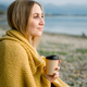 Young blond woman wrapped in blanket holding coffee mug at lakeshore - PhotoDune Item for Sale