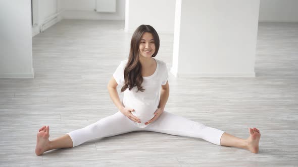 Asian Pregnant Woman in Second Trimester Doing Fitness Excercise Indoors