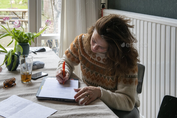 Helping elderly lady fill in forms with the help of laptop and phone ...