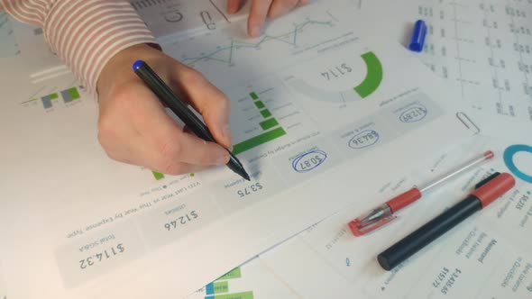 Male Hand is Checking with Marker List of Business Figures in the Office alt