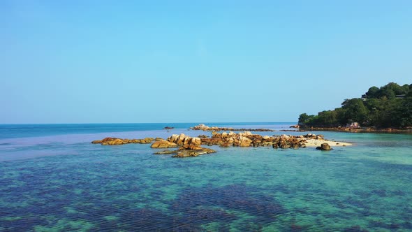 Wide above travel shot of a white sandy paradise beach and blue sea background in hi res 4K alt