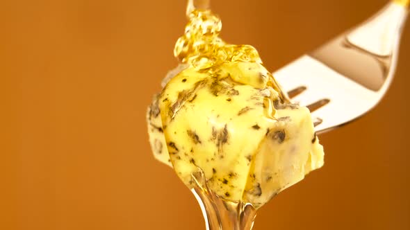 Liquid Organic Honey Dripping on a Fork with Dorbly Cheese on a Light Background alt