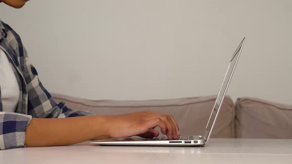 A Woman is Typing on a Laptop Keyboard While Sitting at a Desk at Home