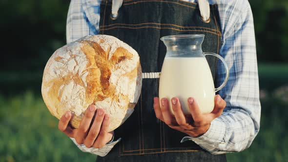 A Farmer Holds a Jug of Milk and a Loba Loaf. Healthy Organic Food alt