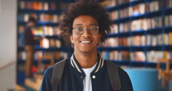 Portrait of Afroamerican Male Student Smiling at Camera in Campus Library alt