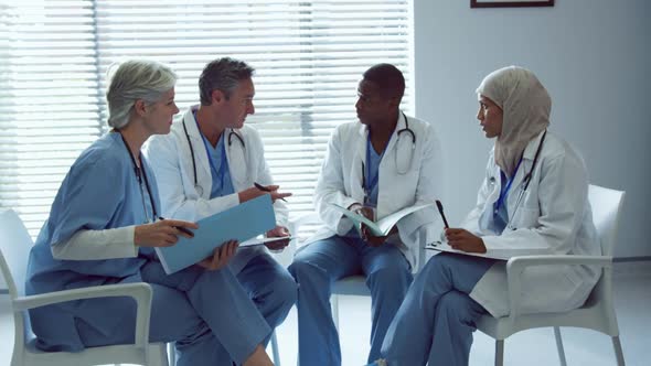 Front view of Multi-ethnic doctors discussing over medical files in hospital alt