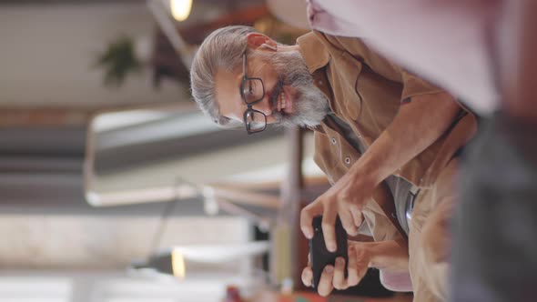 Cheerful Middle Age Man Playing Game on Smartphone alt
