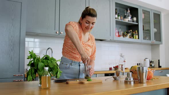 Woman Making Mojito Cocktail Drink at Home Kitchen alt
