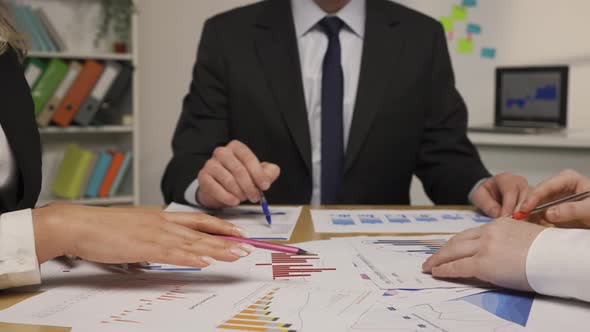 Leader Man and Business Partners Analyze Papers with Charts and Graphs alt