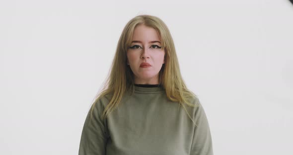 Angry Woman in Green Clothes Makes Funny Grimaces on White alt