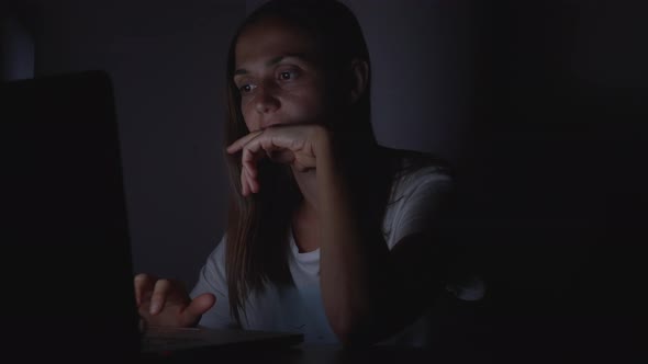 Young Woman Working on Laptop in Darkness