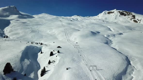 Aerial drone view of ski chair lifts and snow covered mountains in the winter. alt