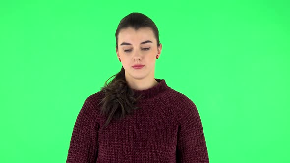 Upset Girl Guilty Lowers Her Eyes on a Green Screen in the Studio. alt