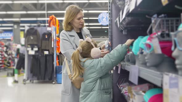 Mother and Daughter Choose Glasses for Swimming in a Store of Goods for Sports alt