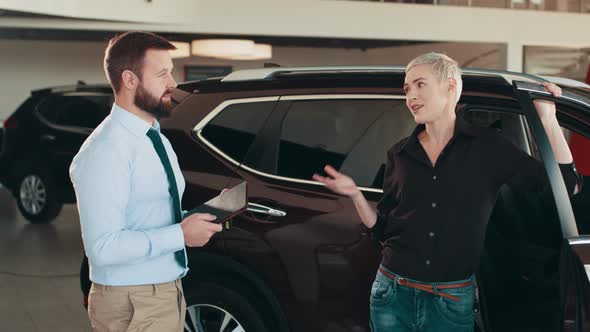 Salesman at the Dealership Showroom Talking with Customer and Helping Her to alt