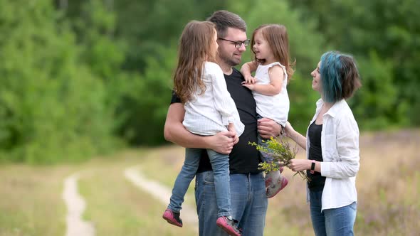 Portrait of Happy young family in a beautiful summer park. Happy Family Walking Outdoors. alt