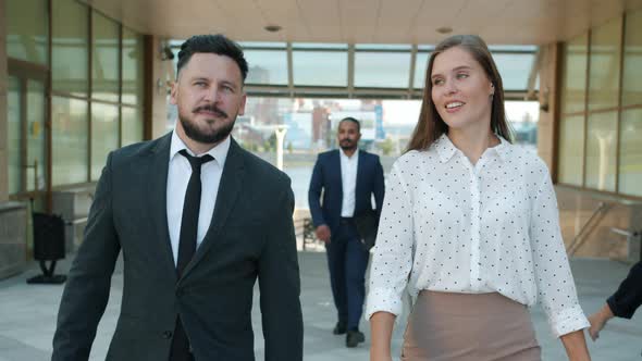 Slow Motion Dolly Shot Portrait of Cheerful Man and Woman Colleagues Walking Outdoors Near Office alt