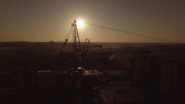 Construction Site at Sunset. Silhouette of a Construction Crane Near the Building