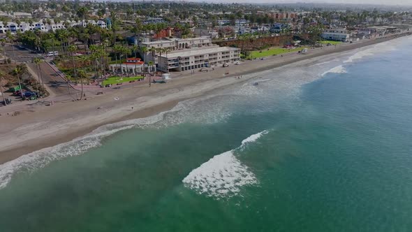 turquoise sea and cityscape of the coastal city of Oceanside, CA, USA. aerial tilt up alt